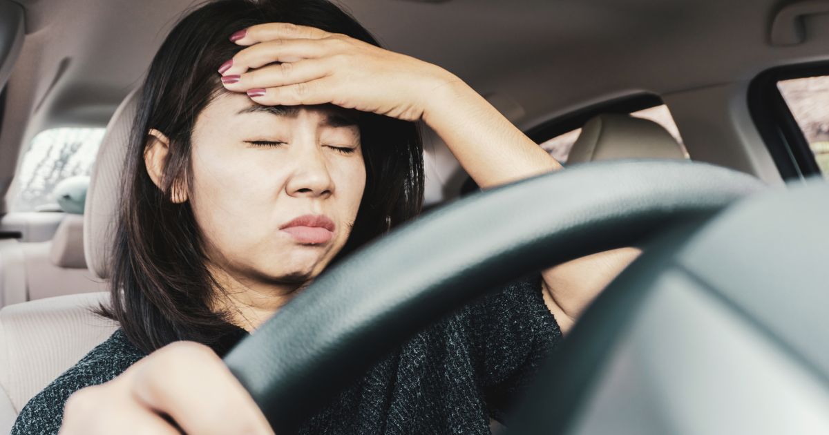 Woman holding head while in car